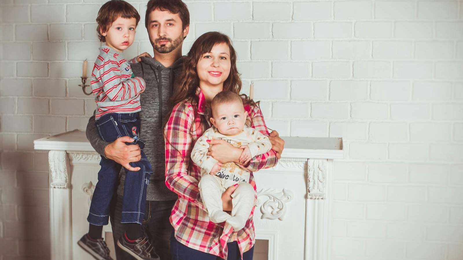 Family smiling for photo in matching plaid outfits.